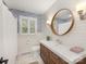 Well-lit bathroom with wooden framed mirror, elegant vanity, and blue wallpaper accent at 1300 Rutledge Ave, Charlotte, NC 28211