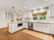 Stylish white kitchen featuring stainless steel appliances, hardwood flooring, and a central island at 1300 Rutledge Ave, Charlotte, NC 28211