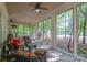 A screened porch or sunroom with wooded views through many windows, and wicker style furniture at 154 Patterson'S Bridge None, New London, NC 28127