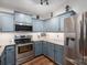 Well-lit kitchen featuring modern stainless steel appliances, blue cabinetry, and granite countertops at 1774 Smyrna Ln, Catawba, NC 28609