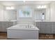 Neutral toned bathroom featuring a soaking tub and double sinks below large mirrors at 2025 Sweet Magnolia Ln, Clover, SC 29710