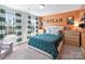 Bright bedroom featuring a comfortable bed with a green comforter, striped curtains, and an orange accent wall with custom lettering at 2025 Sweet Magnolia Ln, Clover, SC 29710