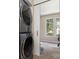 Modern stacked washer and dryer near a light-filled room with large windows and neutral carpet at 216 S Clarkson St # E, Charlotte, NC 28202