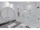 Modern bathroom with glass-enclosed shower, marble-look tile, and a sleek vanity with round mirror at 3524 Rhett Butler Pl, Charlotte, NC 28270