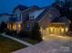 A stunning brick home at twilight features a well-lit driveway and a three-car garage at 4006 Tremont Dr, Indian Trail, NC 28079