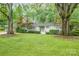 Charming one-story home with mature trees, a lush green lawn, and stylish light blue shutters at 5162 Lincrest Pl, Charlotte, NC 28211