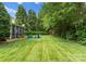 Spacious backyard with lush green lawn, fire pit area, and mature trees at 611 Meadow Lake Dr, Matthews, NC 28105