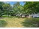 The home's backyard showcases a grassy expanse dotted with mature trees and partial shade at 8221 Brookings Dr, Charlotte, NC 28269