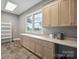 Laundry room with sink, cabinets, tile flooring, and natural light from a window at 8825 Harris Rd, Concord, NC 28027