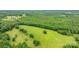 Rolling green field meeting a lush forest, captured from an aerial perspective showcasing the property's natural beauty at 9161 Paul Payne Store Rd, Stony Point, NC 28678