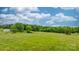 Verdant field with scattered trees under a partly cloudy blue sky, providing a tranquil and scenic natural environment at 9161 Paul Payne Store Rd, Stony Point, NC 28678