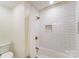 Clean white tiled bathroom with a shower over the tub, gold accents and shower curtain at 10338 Hollybrook Dr, Charlotte, NC 28277