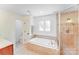 Bright bathroom with tile floors, soaking tub and glass enclosed shower at 10338 Hollybrook Dr, Charlotte, NC 28277