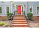 Inviting entryway with brick steps, a red door, manicured bushes, and decorative wall lanterns at 10338 Hollybrook Dr, Charlotte, NC 28277