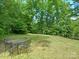 A large backyard featuring a metal table and chair set surrounded by a well maintained lawn and bordered with mature trees at 1061 Nw 14Th Avenue Nw Dr, Hickory, NC 28601
