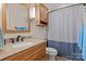 Cozy bathroom with wood vanity, granite countertop, and shower with blue patterned curtain at 1201 Pegram St, Charlotte, NC 28205