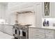 Close up of a gas range with stainless steel hood and cream colored backsplash at 14701 Jockeys Ridge Dr, Charlotte, NC 28277