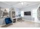 Well-lit home office featuring a desk, shelving unit, comfortable blue chair, and large windows at 14701 Jockeys Ridge Dr, Charlotte, NC 28277