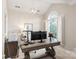 Bright office featuring a rustic desk, unique lighting, arched window, and neutral decor at 14701 Jockeys Ridge Dr, Charlotte, NC 28277