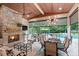 Relaxing covered patio with stone fireplace, mounted TV, and dining area overlooking a lush backyard and pool at 14701 Jockeys Ridge Dr, Charlotte, NC 28277