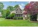 Well-manicured backyard featuring lush grass, mature landscaping, and a screened-in porch at 157 Dedham Loop, Mooresville, NC 28117