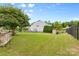 Large backyard featuring a stone grill station, green grass, mature trees, fenced in perimeter, and storage shed at 2042 Newport Dr, Fort Mill, SC 29707