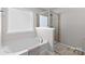 Bright bathroom featuring a soaking tub, glass-enclosed shower, neutral color palette, and natural light from a large window at 2042 Newport Dr, Fort Mill, SC 29707