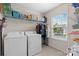 Well-lit laundry room with a washer and dryer, storage shelves, and a window providing a view of the outdoors at 2042 Newport Dr, Fort Mill, SC 29707