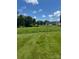 Spacious green backyard with some trees, and a building in the distance under a sunny sky at 206 13Th St, Belmont, NC 28012