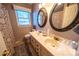 Bathroom featuring dual sinks, decorative mirrors, and a window with natural light at 24264 Strand Dr, Albemarle, NC 28001
