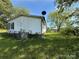 Rear exterior view of a home with white siding and brick foundation surrounded by a lush, overgrown lawn at 33 Honeysuckle Ln, Taylorsville, NC 28681