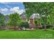 Lush backyard with mature trees, green lawn, and patio area, creating a serene outdoor space for the beautiful brick home at 5508 Kincross Ln, Charlotte, NC 28277
