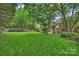 Well-manicured backyard with a large grassy area, mature trees, and landscaping, perfect for relaxation and recreation at 5508 Kincross Ln, Charlotte, NC 28277