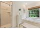 Bright bathroom with a soaking tub, glass-enclosed shower, and large window at 5508 Kincross Ln, Charlotte, NC 28277