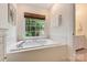Relaxing bathtub with tile surround, a bright window, and storage cabinets at 5508 Kincross Ln, Charlotte, NC 28277