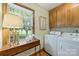 Functional laundry room with wooden cabinets, side table, and a view of the outdoor scenery at 5508 Kincross Ln, Charlotte, NC 28277
