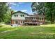 A back exterior shot revealing a two-story brick home with a wooden deck overlooking the lush green lawn at 5772 Gettysburg Nw Dr, Concord, NC 28027