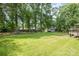 A large, verdant backyard with mature trees, and a glimpse of a wooden deck and a shed at 5772 Gettysburg Nw Dr, Concord, NC 28027