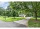 Long driveway view with a two-story brick and siding home, surrounded by mature trees and a green lawn at 5772 Gettysburg Nw Dr, Concord, NC 28027