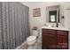 Bathroom includes a toilet next to a vanity with a sink and a shower with a patterned shower curtain at 5812 Camp Sw Ct, Concord, NC 28025