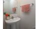 Bathroom features a pedestal sink with neutral walls, complemented by a mirror and decorative flowers and hand towels at 5812 Camp Sw Ct, Concord, NC 28025