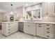 Charming kitchen with a stainless steel dishwasher, pristine white cabinets, and a well-lit window enhancing the bright atmosphere at 64 Timberidge Dr, Lake Wylie, SC 29710