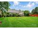 Expansive backyard with a lush lawn, manicured shrubs and trees, and a cozy patio area for relaxing or entertaining at 6717 Bickham Ln, Charlotte, NC 28269