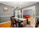 Dining room featuring a dark wood table with a floral runner, chandelier, and view into the living room at 6717 Bickham Ln, Charlotte, NC 28269