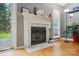 Elegant white fireplace with marble surround and hearth, complemented by a window, plant and hardwood floors at 6717 Bickham Ln, Charlotte, NC 28269