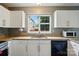 Well-lit kitchen featuring granite countertops, white cabinets and a window overlooking the backyard at 6717 Bickham Ln, Charlotte, NC 28269