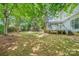 A spacious backyard featuring lush green grass, mature trees, play set, and a charming deck and screened in porch at 8709 Huntland Ct, Charlotte, NC 28277