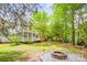 A backyard featuring mature trees, green grass, a play set, a wooden fence, a charming screened in porch and a fire pit at 8709 Huntland Ct, Charlotte, NC 28277