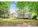 A spacious backyard featuring mature trees, green grass, a play set, a wooden fence, and a charming screened in porch and deck at 8709 Huntland Ct, Charlotte, NC 28277