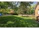 Large grassy backyard featuring a wooden fence, mature trees, and well-maintained lawn at 1208 Chausley Ct, Charlotte, NC 28211
